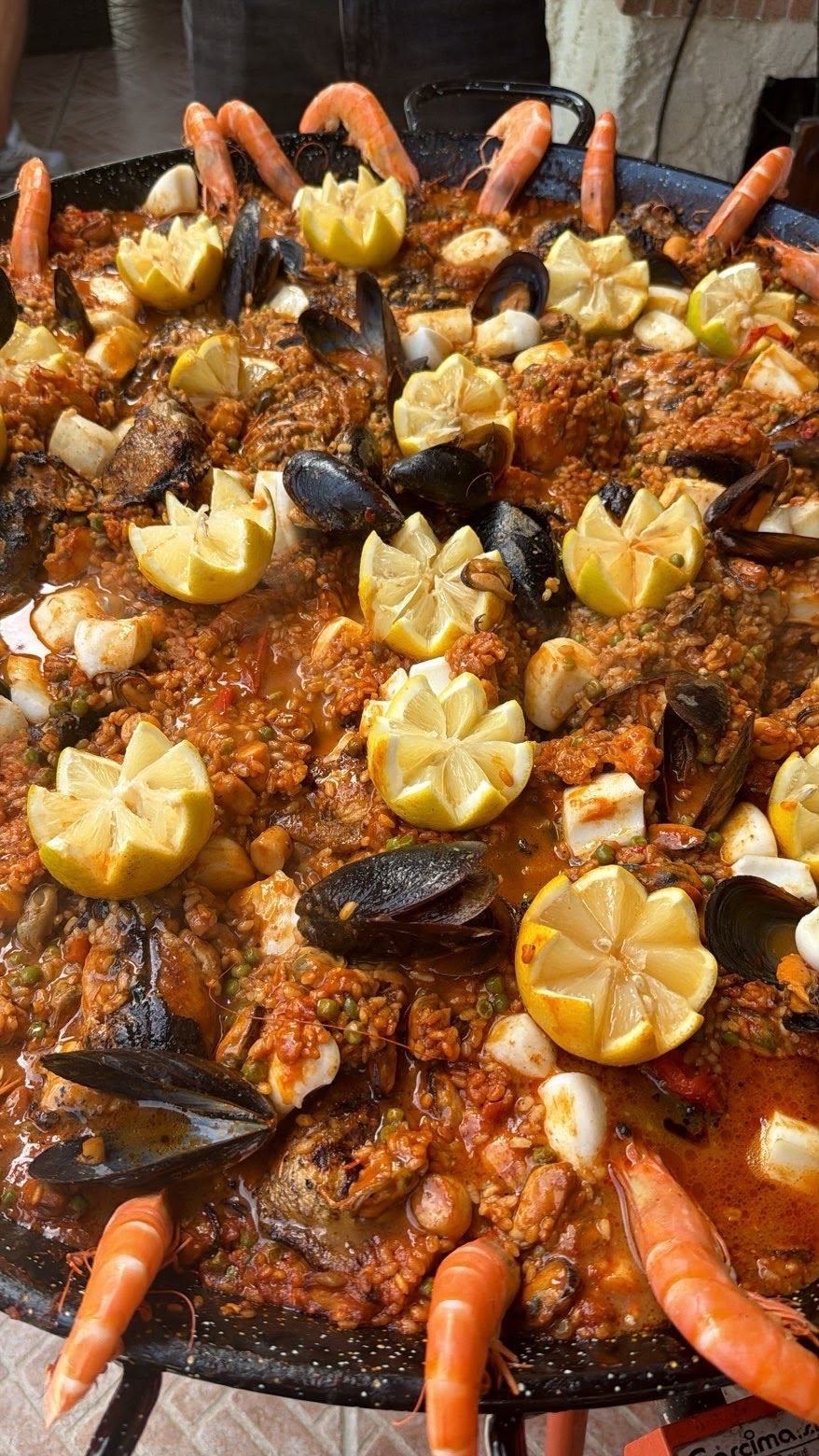 Gros plan sur une paella généreuse garnie de crevettes, moules et citrons